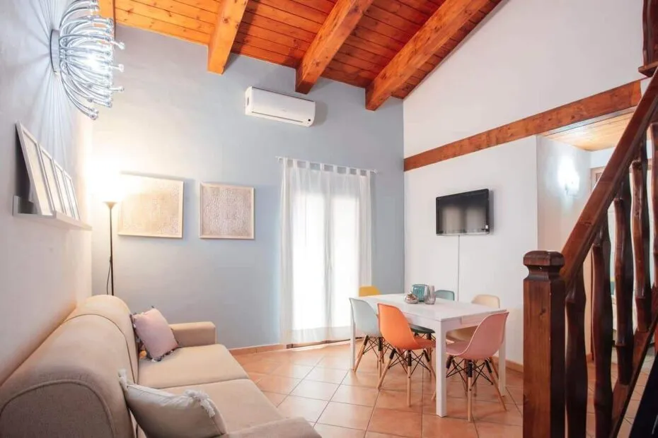 Soggiorno con travi in legno a vista, divano e tavolo da pranzo colorato