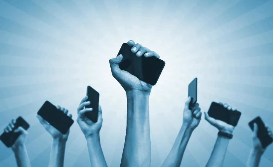 Diverse mani alzate che reggono smartphone su sfondo blu, simbolo della rivoluzione digitale