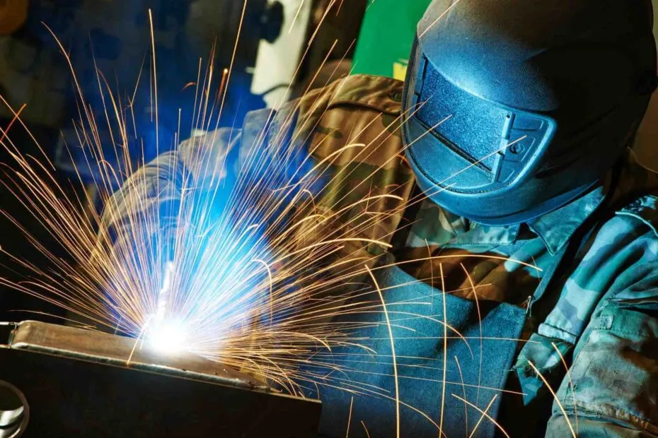 Saldatore al lavoro con maschera protettiva tra le scintille della saldatura